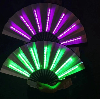 Twee lichtgevende led-waaiers in roze en groen in de hand