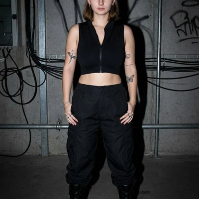 Model in zwarte Rave Zip Top, rechte pose, club- en festivalstijl