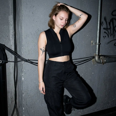 Rave Zip Top zwart, model leunt tegen muur, techno-clubsfeer
