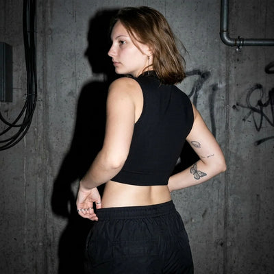 Zijaanzicht van de zwarte Rave Zip Top, model in urban setting