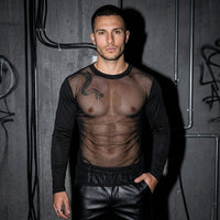 Zwart Sheer Vibe longsleeve met transparant lijf, vooraanzicht bij model voor betonnen muur